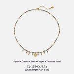 A beaded necklace with small multicolored stones and gold-tone charms, displayed on a light gray background with product text below. The necklace features a gold clasp and extender chain.