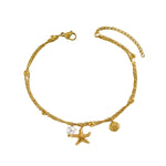 A gold chain anklet featuring a lobster clasp, extender chain, small bead accents, a starfish charm, a seashell charm, and a small white pearl bead.