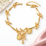 Gold necklace with leaf-like designs on a beige background