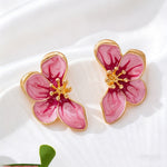 Pink flower-shaped earrings with gold accents on a white background